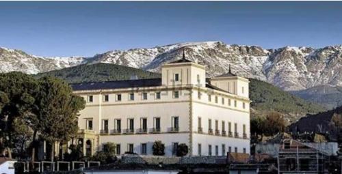 a large white building with mountains in the background at Vivienda Vacacional Triste Condesa in Arenas de San Pedro