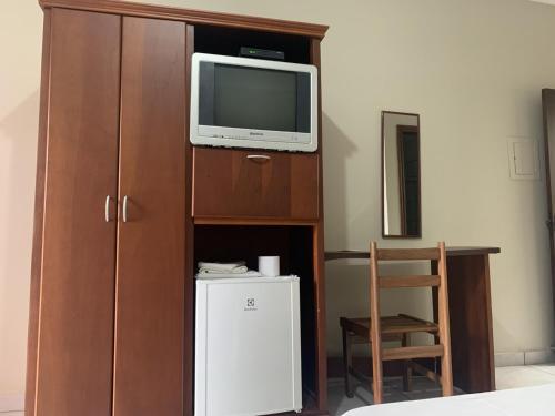 a room with a tv and a cabinet with a refrigerator at Ouro Hotel in Ourinhos