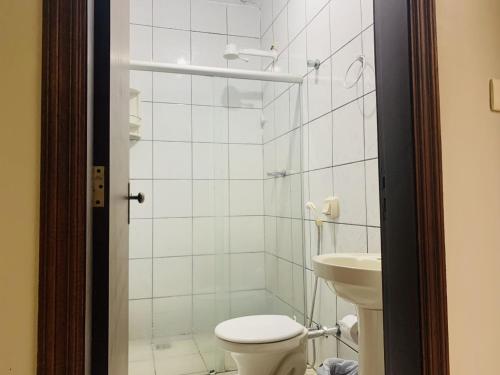 Baño blanco con aseo y lavamanos en Ouro Hotel en Ourinhos