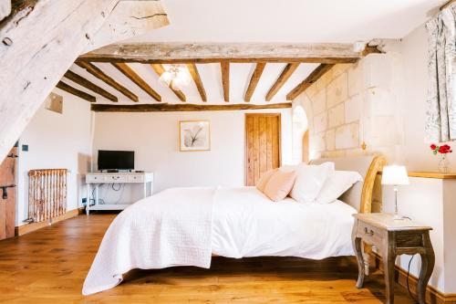 a bedroom with a white bed and a wooden floor at Manoir de Jouralem in Blaison