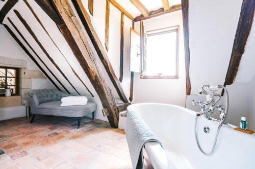 a bathroom with a white tub and a chair at Manoir de Jouralem in Blaison