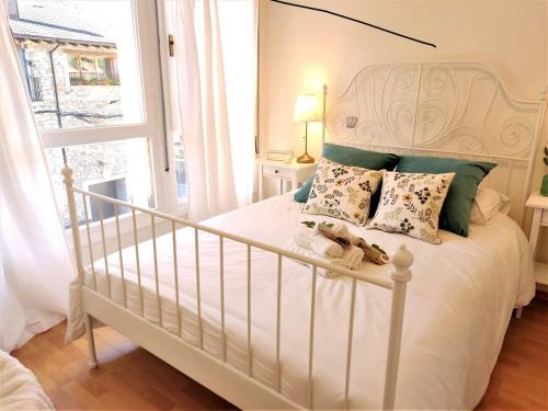 Un dormitorio con una cama blanca con almohadas y una ventana en Noa Apartment En el corazón de los Pirineos, en Adrall