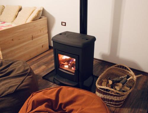 a wood stove in a room with a basket of logs at Vila Janko 1 in Voskopojë