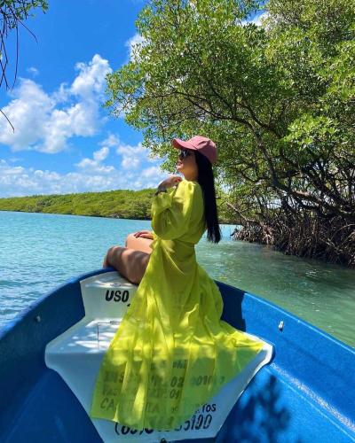 a woman in a yellow dress sitting on a boat at Mar de Gente Pousada in Praia de Moitas