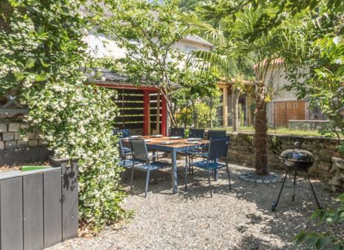 a patio with a table and chairs and a grill at gite cosy et moderne au coeur des pyrénées in Chaum