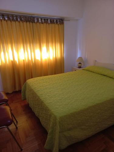 Un dormitorio con una cama verde y una ventana en Departamento céntrico luminoso en Mar del Plata