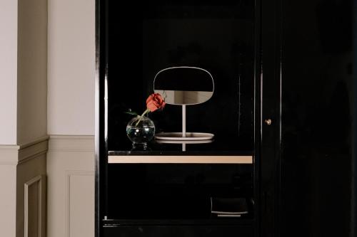 a mirror and a vase on a shelf in a black cabinet at Maison Matilda - Luxury Rooms in Treviso