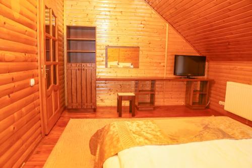 a bedroom with a bed and a tv in a wooden cabin at Erney Laz Hotel in Shaian