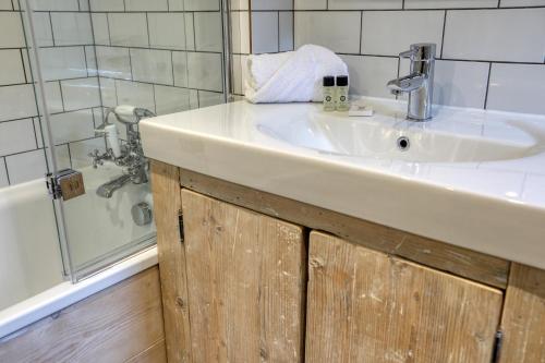 La salle de bains est pourvue d'un lavabo blanc et d'une douche. dans l'établissement Ostlers Loft, à Chipping Campden