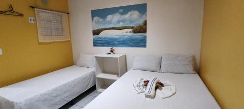 a bedroom with two beds and a painting on the wall at Pousada Amar Lençóis Turismo in Barreirinhas