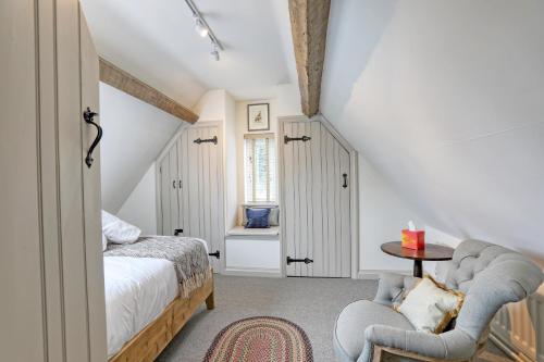 a bedroom with a bed and a chair and a table at Ostlers Loft in Chipping Campden