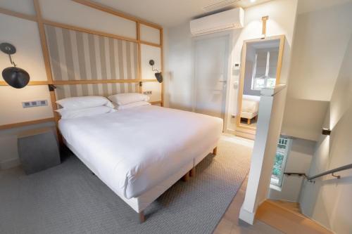 a bedroom with a large white bed and a mirror at Le Grand Pavillon Chantilly in Chantilly