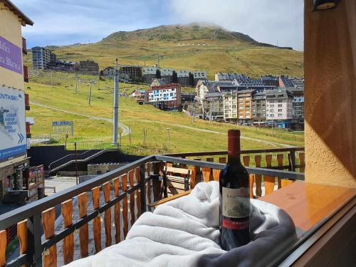 Una botella de vino sentada en una mesa en un balcón en SkiinSkiout Wifi Guardaesquís y Relax TETRAS en Pas de la Casa
