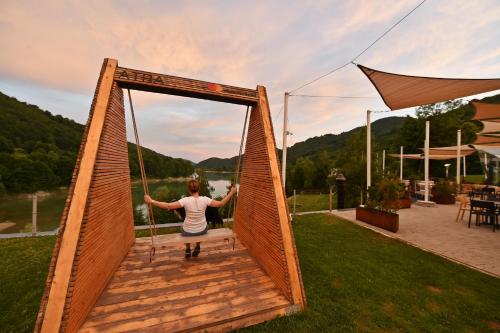 a woman is swinging on a wooden swing at Pensiunea Atra Doftana in Teşila