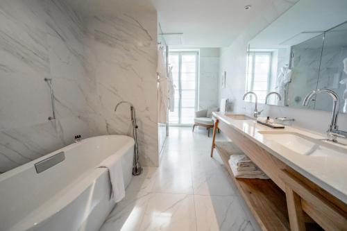 a bathroom with two sinks and a bath tub at Le Grand Pavillon Chantilly in Chantilly