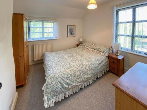 a bedroom with a bed and two windows at Willow Cottage in Ironbridge