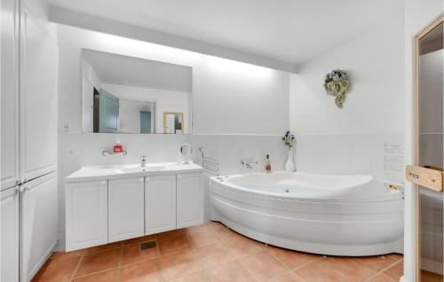 Baño blanco con bañera y lavamanos en Beautiful Apartment In Ringkbing With Sauna, en Søndervig