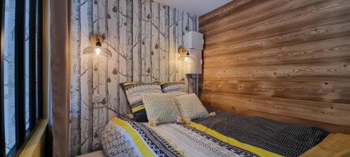 a bedroom with a wooden wall and a bed with pillows at Elégant et moderne, au pied du Mont-Blanc in Saint-Gervais-les-Bains