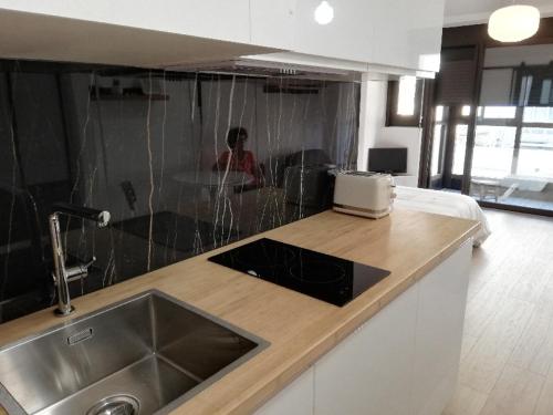 a kitchen with a counter with a sink and a woman at Appartement '' L'Ossau '' hyper centre Place Clémenceau in Pau