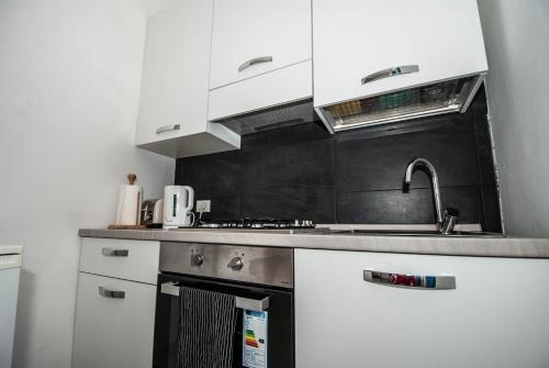 a kitchen with white cabinets and a stove top oven at Casa Di Mezzo by Arbaspàa in Manarola