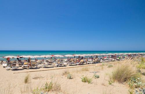 a beach with chairs and umbrellas and the ocean at Paradù EcoVillage & Resort in Marina di Castagneto Carducci