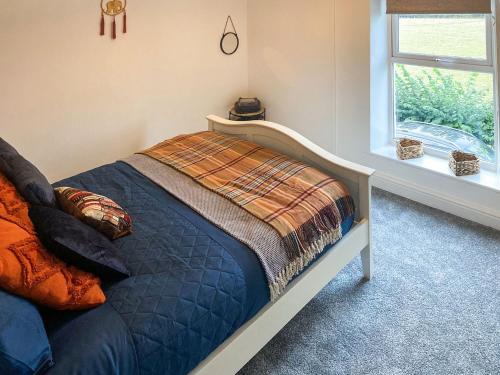 a bedroom with a bed with a blanket and a window at Quarrymans in Llysfaen