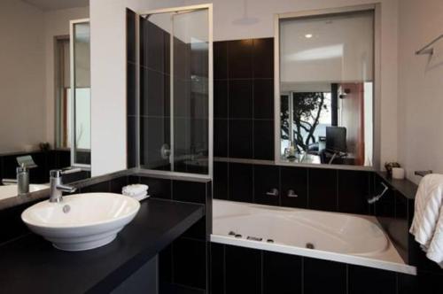 a bathroom with a sink and a bath tub at Battery Cove Beach Front Apartment in Port Fairy