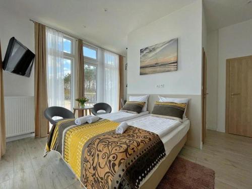 a bedroom with a large bed with two chairs at Pokoje na plaży in Ustronie Morskie