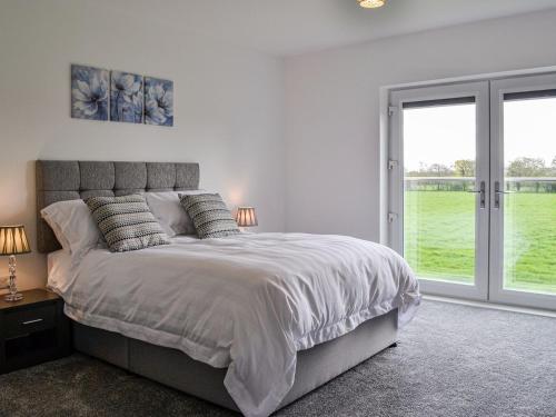 a white bedroom with a large bed and sliding glass doors at Chestnuts in Burgh by Sands