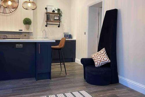 una cucina con bancone, sedia e lavandino di The Apartment - Brand new, stylish & central a Shanklin