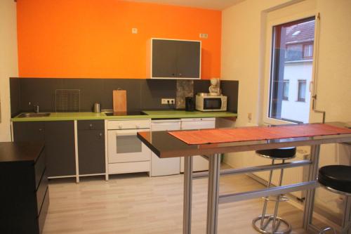 a kitchen with orange walls and a table with chairs at FEWO Steile WH 2 Wand 106 Meerane in Meerane