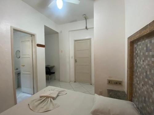 Habitación blanca con cama y espejo en Hotel Bom Gosto, en Salvador
