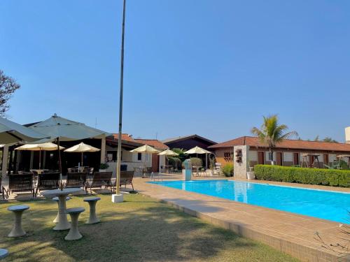 a swimming pool with tables and chairs and umbrellas at Pousada Mirante das Estancias in Águas de Lindóia