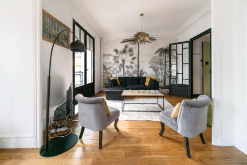 een woonkamer met 2 stoelen en een bank bij Résidence Le Paris - Appartements centre ville in Vichy