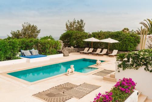 a pool with chairs and umbrellas in a backyard at Casa Sua in Famara