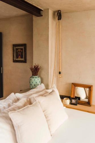 a bed with white pillows and a vase with a mirror at Casa Sua in Famara