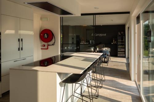 a kitchen with white cabinets and a counter with stools at Logies Ternier in Nieuwpoort