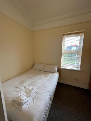 een kleine slaapkamer met een wit bed en een raam bij East City Flat in Dublin