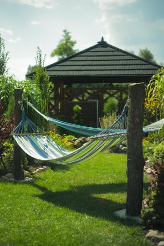 a hammock in a garden with a gazebo at Zielono Mi Apartament z kominkiem & Pokoje z pięknym widokiem in Janowiec