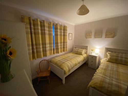 een slaapkamer met twee bedden en een stoel en een raam bij Osborne Cottage in Southend