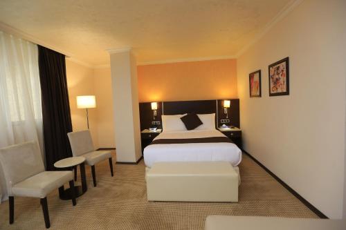 een hotelkamer met een bed en een stoel bij Cassiopeia Hotel in Addis Ababa