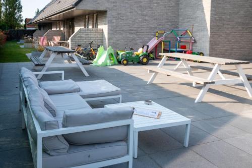 a patio with two picnic tables and a playground at Logies Ternier in Nieuwpoort