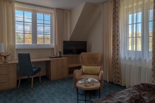 a hotel room with a bed and a desk and a tv at Highland Warmia - Gospodarstwo agroturystyczne in Jeziorany