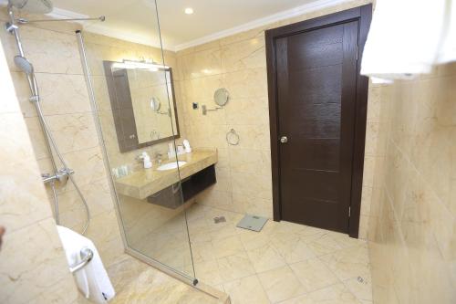 uma casa de banho com um chuveiro e uma porta de vidro em Cassiopeia Hotel em Addis Ababa