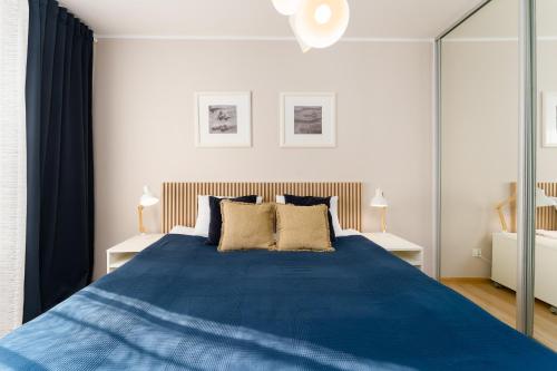 a bedroom with a large blue bed with two lamps at Przystań Koło Brzegu in Kołobrzeg