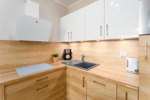 a kitchen with white cabinets and a sink at Przystań Koło Brzegu in Kołobrzeg