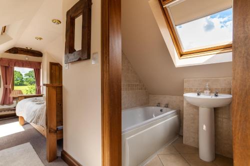 a bathroom with a sink and a bath tub and a window at Coach House at Oaks Barn Farm Alcester with optional hire Salt water hot tub 