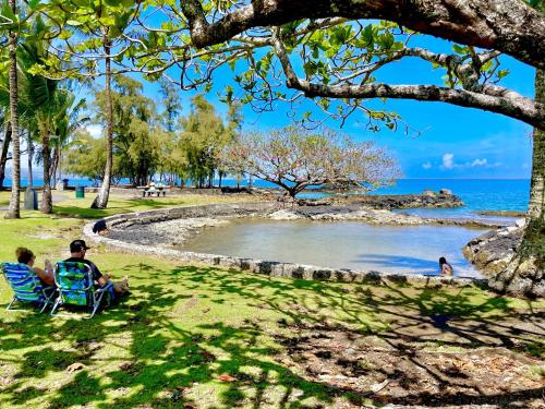 people sitting in a chair on the grass by the water at Pua Lani in Keaau
