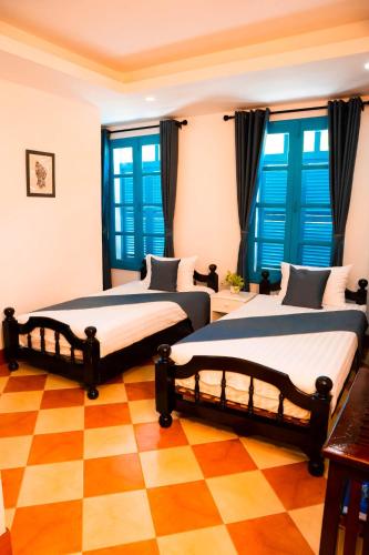 two beds in a room with a checkered floor at Villa Merry Lao Ban Aphay in Luang Prabang