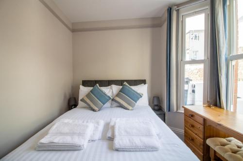 a bedroom with a bed with two pillows and a window at Sea La Vie- Cosy, Modern, Harbourside Views in Brixham